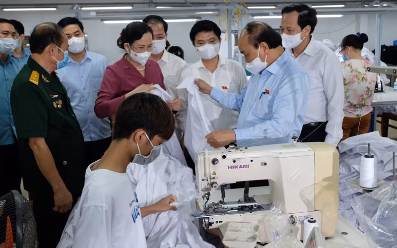Ngày 23/7, Chủ tịch nước Nguyễn Xuân Phúc đến thăm doanh nghiệp may mặc Hoàng Tuyên tại tỉnh Hà Nam, do thương binh làm kinh tế giỏi Hoàng Văn Tuyên làm chủ. (Ảnh: Đào Phương)