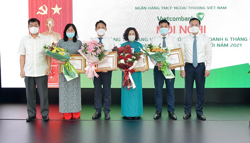 Đồng chí Nguyễn Đức Phong – Phó Bí thư Đảng ủy Khối Doanh nghiệp Trung ương (ngoài cùng bên trái) và đồng chí Phạm Quang Dũng – Phó Bí thư phụ trách Đảng bộ, Tổng Giám đốc Vietcombank (ngoài cùng bên phải) trao Bằng khen của Đảng ủy Khối và tặng hoa chúc mừng cho các tổ chức đảng đạt danh hiệu “Trong sạch, vững mạnh” tiêu biểu 5 năm liền (2016-2020) và đảng viên đạt danh hiệu “Hoàn thành xuất sắc nhiệm vụ” 5 năm liền (2016 – 2020). Vietcombank quyết tâm hoàn thành “nhiệm vụ kép” trong 6 tháng cuối năm -0