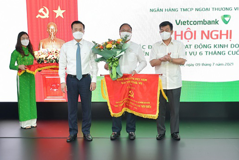 Đồng chí Nguyễn Đức Phong – Phó Bí thư Đảng ủy Khối Doanh nghiệp Trung ương (ngoài cùng bên phải) và đồng chí Phạm Quang Dũng – Phó Bí thư phụ trách Đảng bộ, Tổng Giám đốc Vietcombank (ngoài cùng bên trái) trao Cờ của Đảng ủy Khối và tặng hoa chúc mừng tổ chức đảng đạt danh hiệu “Trong sạch, vững mạnh” tiêu biểu 5 năm liền (2016-2020). Vietcombank quyết tâm hoàn thành “nhiệm vụ kép” trong 6 tháng cuối năm -0