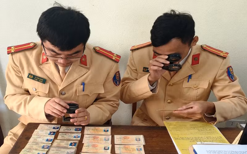 Cảnh sát giao thông sử dụng thiết bị chuyên dụng để quan sát, nhận diện dấu hiệu bất thường của giấy phép lái xe.