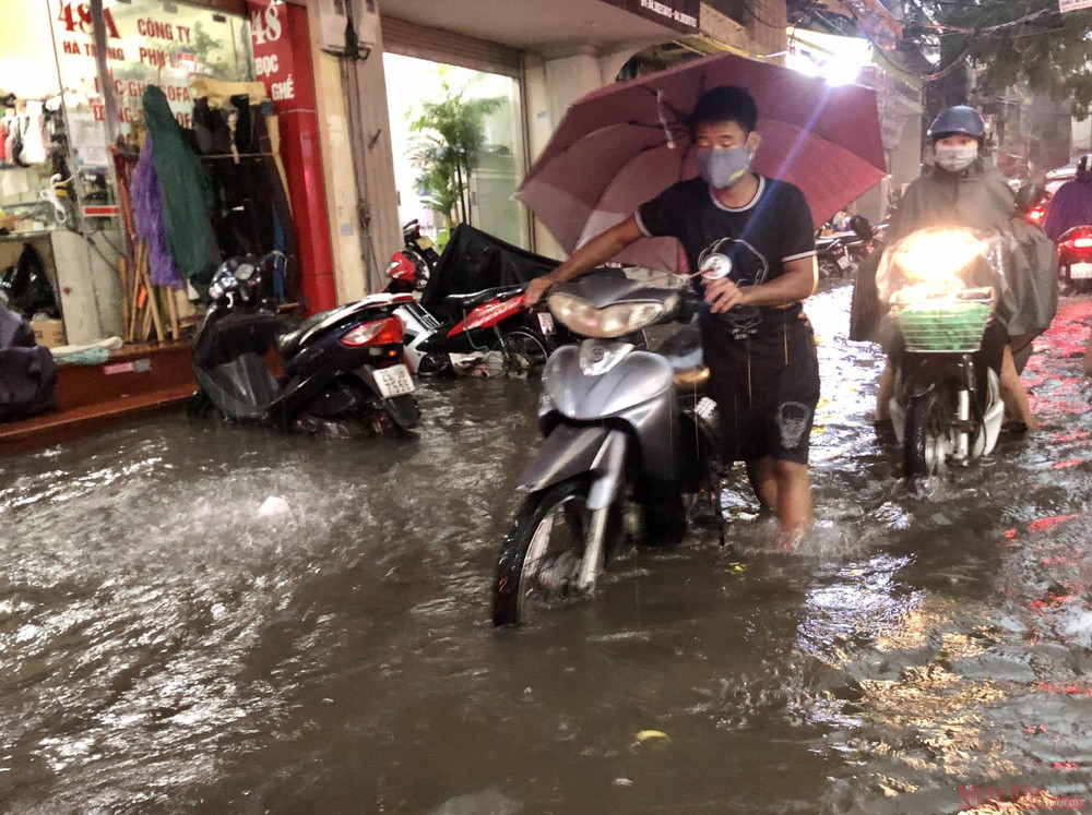 Nhiều phương tiện giao thông chết máy phải dắt bộ qua đoạn ngập trên phố Hà Trung. Ngập sâu, ùn tắc giao thông sau trận mưa lớn tại Hà Nội -9