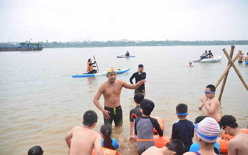 Nguyễn Ngọc Khánh hướng dẫn từng động tác bơi cho các em nhỏ trên sông Hồng.