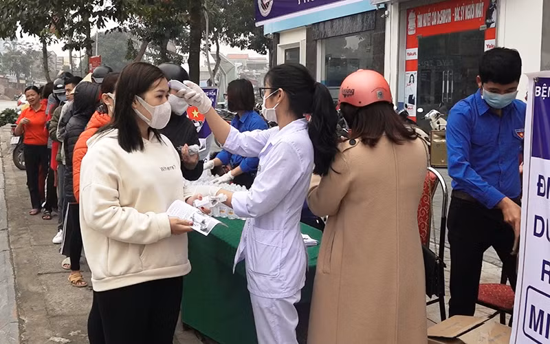 Nhân viên y tế kiểm tra thân nhiệt, cấp phát vật tư phòng dịch cho nhân dân ở huyện Hoằng Hóa.