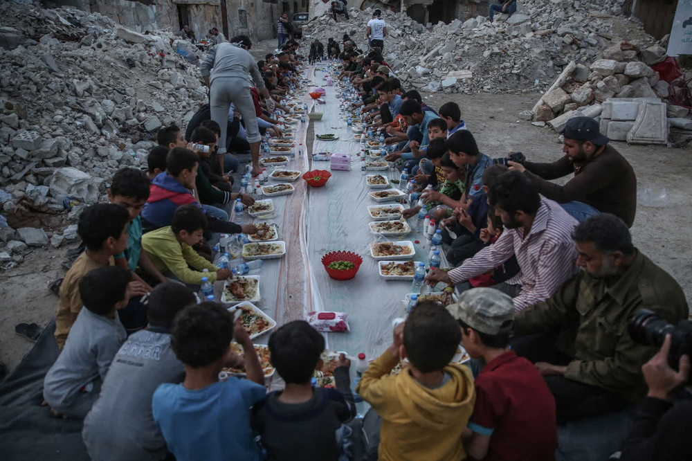 Người dân tại huyện Al-Atarib, Syria, cùng ăn uống trong tháng lễ Ramadan. Các chiến dịch quân sự đã tàn phá nhà cửa của họ. (Ảnh: Getty Images) 1 -0