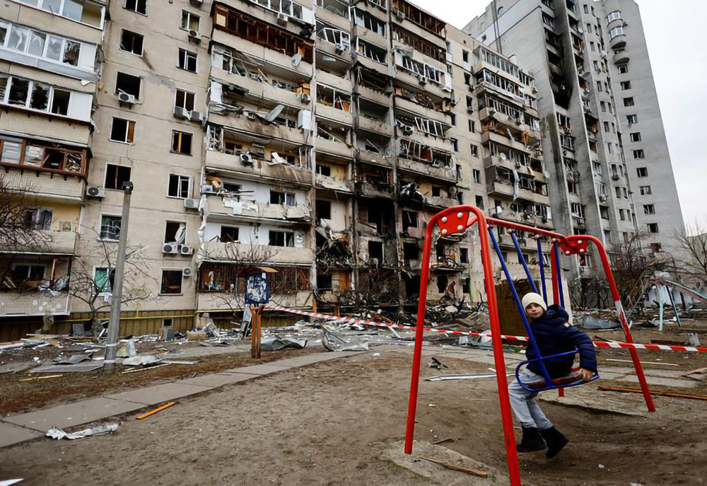 Cậu bé đang chơi xích đu trước một tòa chung cư bị hư hại tại Kiev. (Ảnh: Reuters) Bảy ngày chiến sự tại Ukraine -0