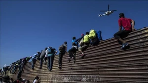 Người di cư trèo qua bức tường biên giới Mexico-Mỹ, gần cửa khẩu El Chaparral ở Tijuana, bang Baja California, Mexico. (Ảnh tư liệu: TTXVN)