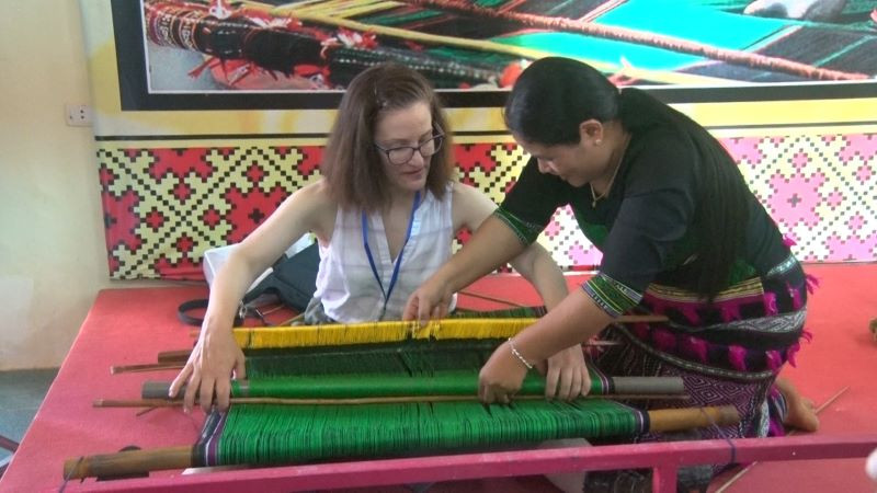 Du khách nước ngoài thích thú khi được nghệ nhân người M’nông giới thiệu, trực tiếp hướng dẫn các thao tác dệt thổ cẩm.