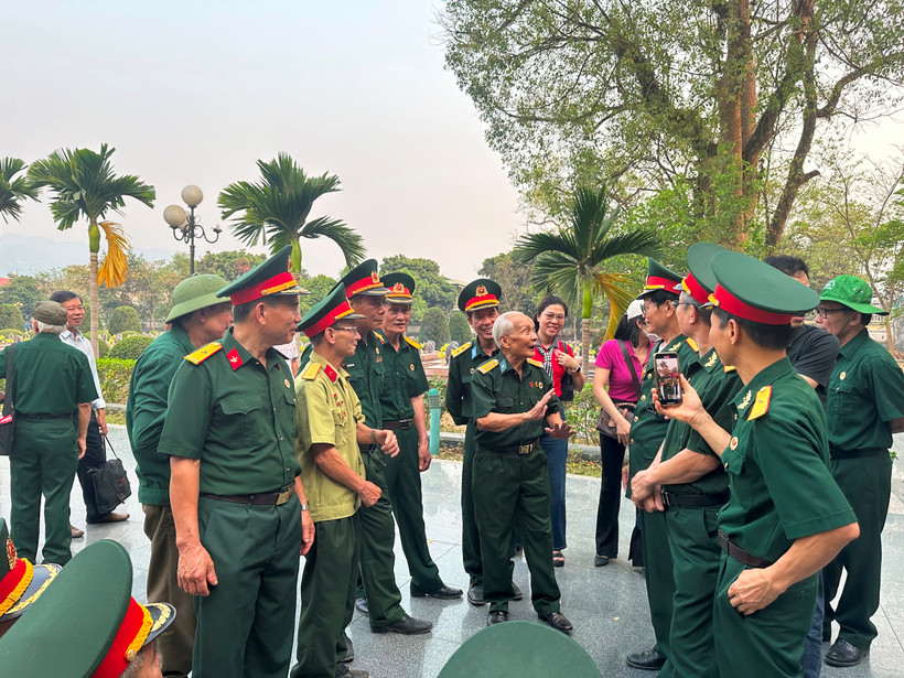 Trong khuôn viên Nghĩa trang Liệt sĩ Điện Biên Phủ, ông Dương Chí Kỳ (người ở giữa) đang kể chuyện đào hào trên đồi A1.