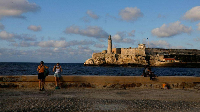 Du khách đeo khẩu trang sau khi chụp ảnh tại đại lộ El Malecon ven biển, ngày 7/2/2022. (Ảnh: Reuters)