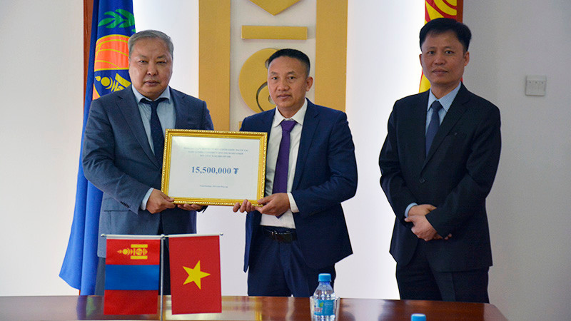 Ông Phạm Quyết Tiến, đại diện cộng đồng người Việt Nam tại Mông Cổ trao khoản tiền quyên góp cho Tổng Cục trưởng NEMA Mông Cổ G.Ariunbuyan trước sự chứng kiến của Đại sứ Việt Nam tại Mông Cổ Doãn Khánh Tâm. (Ảnh: Đại sứ quán Việt Nam tại Mông Cổ)