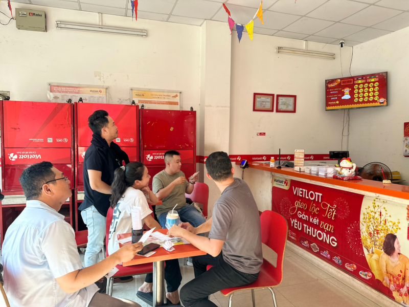 Bên trong một điểm bán vé số Vietlott có đông đảo người chơi theo dõi kết quả mở thưởng Keno trực tiếp trên màn hình.