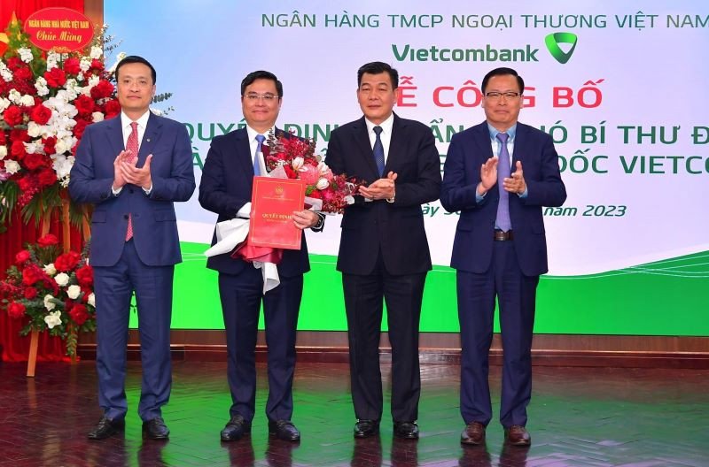 Phó Bí thư Thường trực Đảng ủy Khối doanh nghiệp Trung ương Nguyễn Đức Phong (thứ 2 từ phải sang) trao Quyết định của Đảng ủy Khối doanh nghiệp Trung ương và Chủ tịch HĐQT Vietcombank Phạm Quang Dũng (ngoài cùng bên trái) tặng hoa chúc mừng.