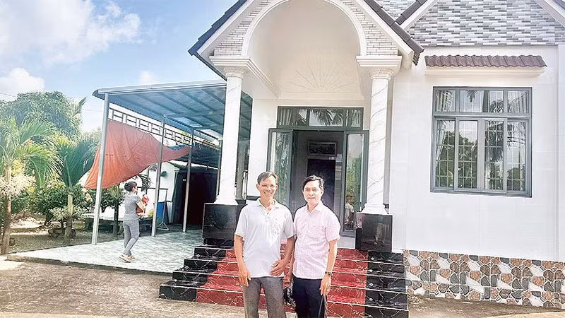 Nông dân Trần Quốc Thống (bên trái) trồng lúa ST 25 kết hợp nuôi tôm, mỗi năm thu lãi hơn một tỷ đồng, vừa xây nhà mới khang trang.