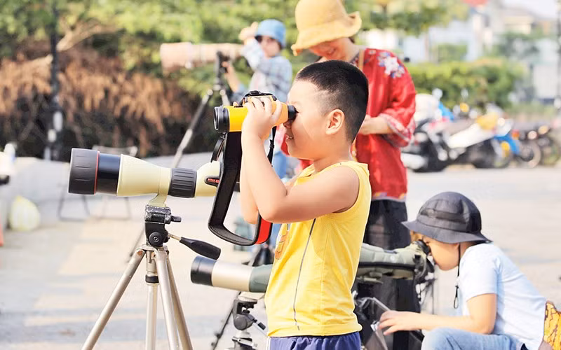 Các em nhỏ trải nghiệm ống nhòm chuyên dụng.