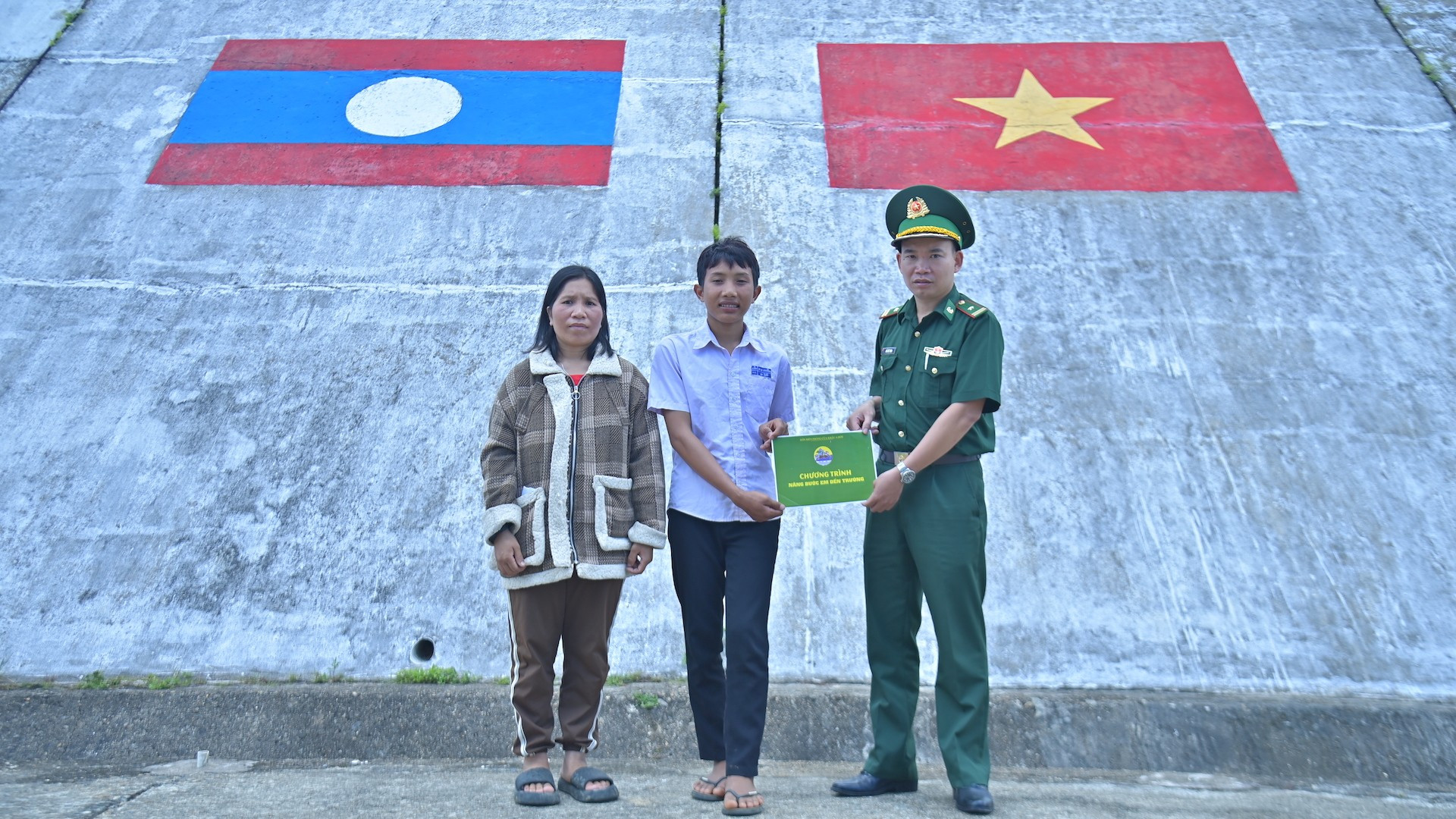 Chiến sĩ Biên phòng thành phố Huế trao quà chương trình "Nâng bước em đến trường" cho em Thạo A Rọt (Lào). ky-3-em-ta-rottrao-ho-tro-nang-buoc-em-toi-truong-cho-hoc-sinh-ban-ka-lo-lao-3-1-copy.jpg
