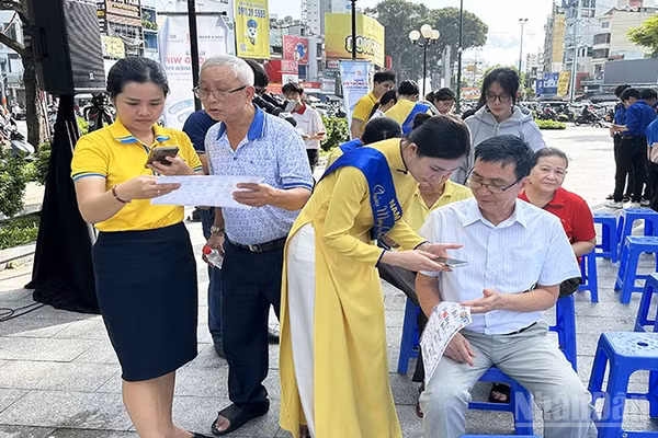 Thanh niên tình nguyện và học sinh hỗ trợ người dân phường Chợ Quán tiếp cận và sử dụng các ứng dụng, tiện ích số thiết yếu. (Ảnh: HOÀNG LIÊM)