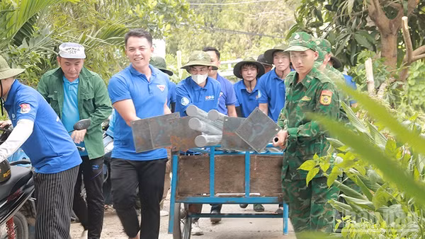 Đoàn viên, thanh niên Đồn Biên phòng Cầu Muống phối hợp cùng Phường đoàn Thường Lạc và đội hình “Mùa hè xanh” của Trường cao đẳng Công nghệ Thủ Đức vận chuyển trụ đèn thực hiện Công trình thắp sáng đường quê. (Ảnh: Phường đoàn Thường Lạc)