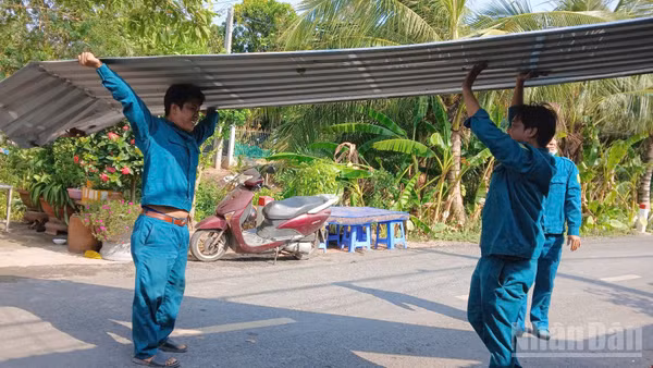 Lực lượng chức năng xã Tân Long giúp người dân lợp lại mái nhà do ảnh hưởng dông lốc.