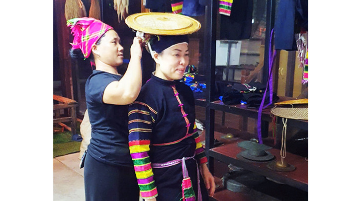 Du khách trải nghiệm mặc thử trang phục truyền thống dân tộc Lô Lô tại huyện Bảo Lạc.
