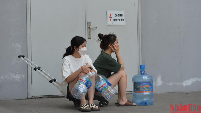 Để có nước dùng, người dân đã phải huy động cả can, xô, thùng nhựa… rồi xếp hàng, hứng từng lít nước từ bể chứa ngầm của tòa nhà về sử dụng trong lúc đợi hệ thống cấp nước… "khỏe" trở lại. Trong ảnh, hai cư dân ngồi chờ đến lượt của mình. Trên tay họ là các chai Lavie đã dùng hết.