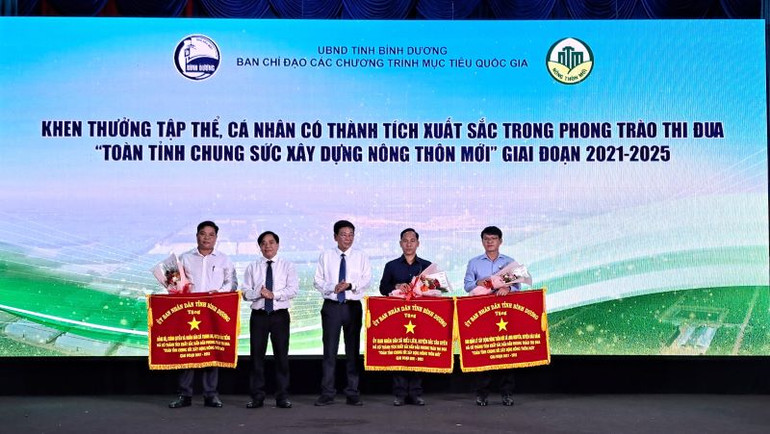 Phó Chủ tịch Thường trực Ủy ban nhân dân tỉnh Bình Dương Mai Hùng Dũng (đứng giữa) trao tặng Cờ thi đua cho ba tập thể xuất sắc tiêu biểu.