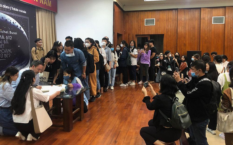 Bạn đọc xếp hàng dài để chờ nhà văn ký tặng sách.