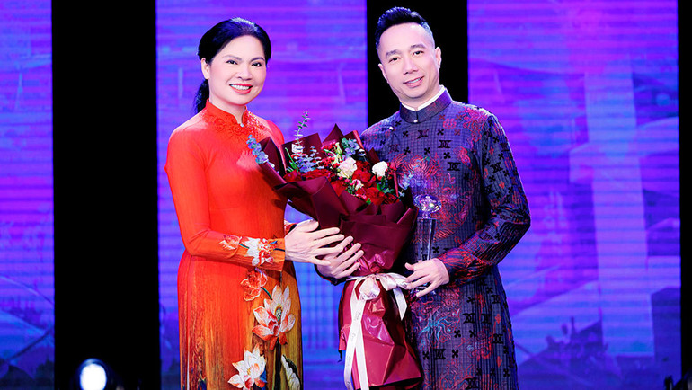 Chủ tịch Hội Liên hiệp phụ nữ Việt Nam Hà Thị Nga trao hoa và kỷ niệm chương cho nhà thiết kế Đỗ Trịnh Hoài Nam.