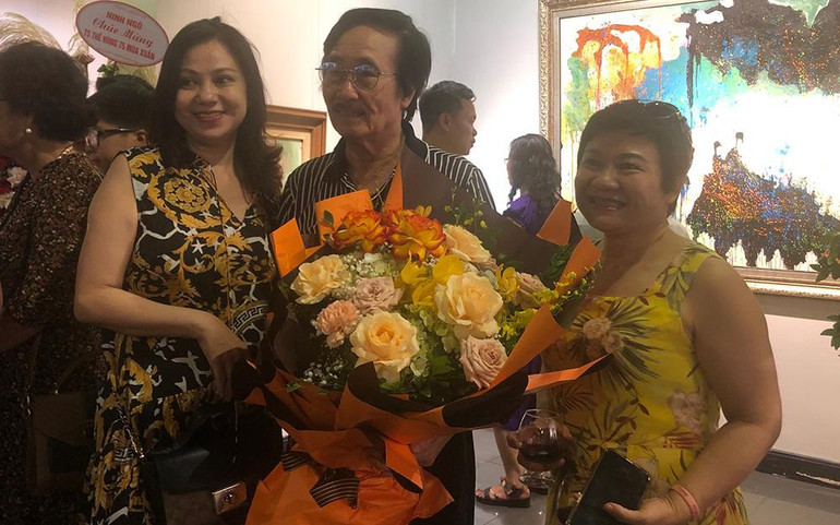Họa sĩ Thế Hùng (giữa) tại triển lãm.