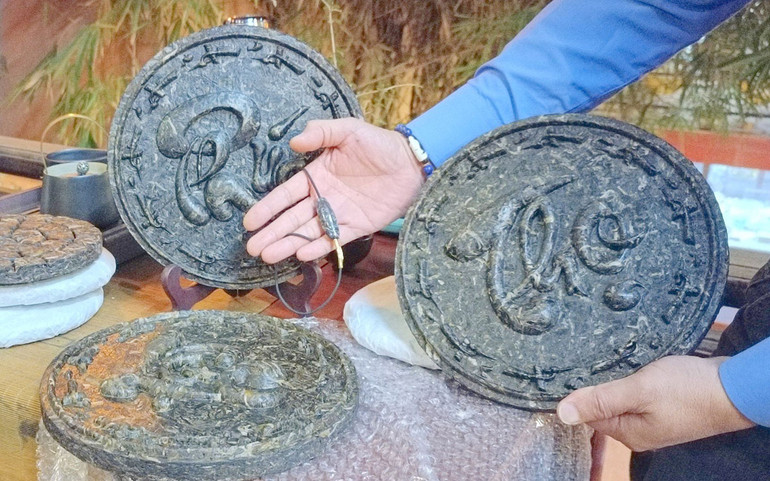 Trà phổ nhĩ được đóng thành bánh có chữ thư pháp để làm quà biếu dịp Tết. (Ảnh: PHAN HỒNG)