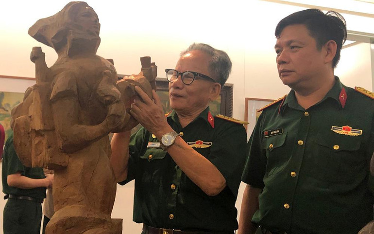 Họa sĩ Lê Duy Ứng cùng bức tượng của mình tại triển lãm.