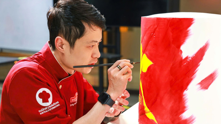 Nghệ nhân Bàn Văn Quỳnh đang hoàn thành chiếc bánh vẽ trang trí có hình ảnh cầu thủ Nguyễn Xuân Son mặc chiếc áo số 12.