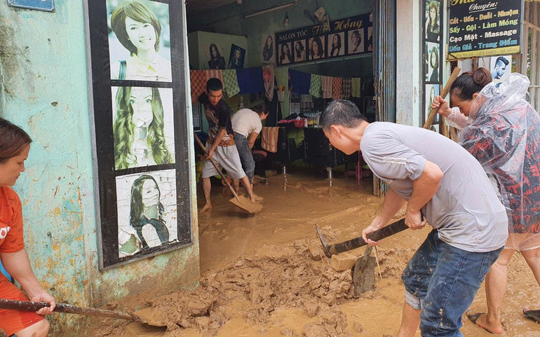 Người dân dọn dẹp bùn đất khi nước rút.