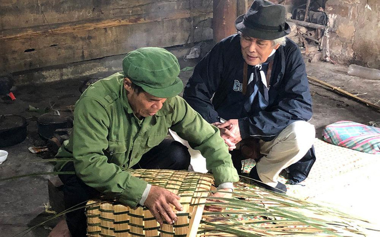 Họa sĩ Đỗ Đức (bên phải) trò chuyện cùng chủ nhà Lâm A Liên về quá trình làm chiếc gùi tre. Họa sĩ Đỗ Đức (bên phải) trò chuyện cùng chủ nhà Lâm A Liên về quá trình làm chiếc gùi tre.