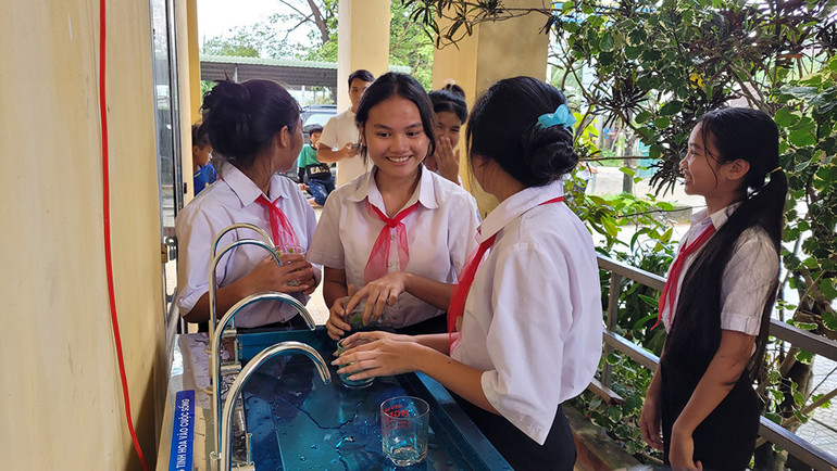 Các em học sinh háo hức sử dụng máy lọc nước.