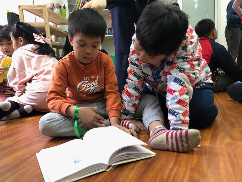 Hai em nhỏ đang đọc cuốn "Trò chơi của trẻ em ở Bắc Kỳ”.