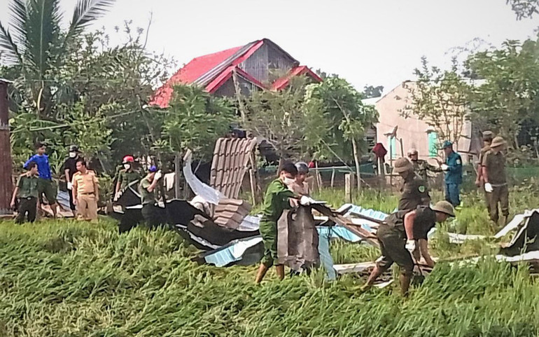 Lực lượng Công an huyện Phú Thiện hỗ trợ người dân dọn dẹp những mái tôn bị lốc xoáy cuốn.