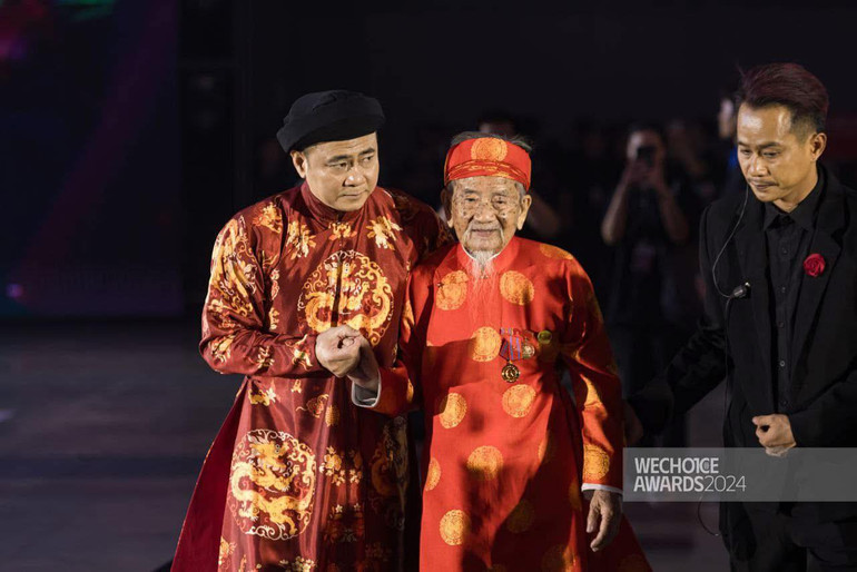 NSND Tự Long đỡ nhà nghiên cứu Nguyễn Đình Tư lên nhận giải thưởng. (Ảnh: We Choice Award)