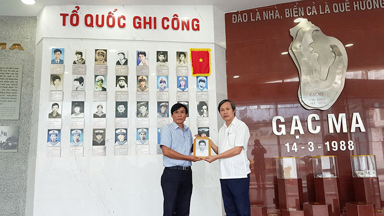 PGS, TS Ngô Văn Minh, Học viện Chính trị Khu vực III (bên phải) trao di ảnh liệt sĩ Trần Quốc Trị tặng Ban Quản lý Khu tưởng niệm chiến sĩ Gạc Ma. (Ảnh: NGUYỄN VĂN NGỌC)