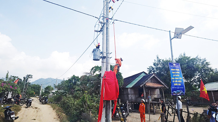 Nhân viên điện lực thao tác đấu nối điện cho dân làng.