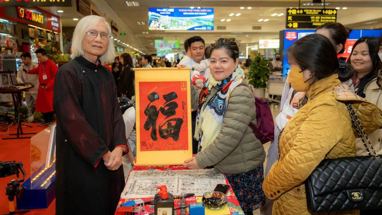 Tặng chữ thư pháp cho hành khách đi tàu bay.