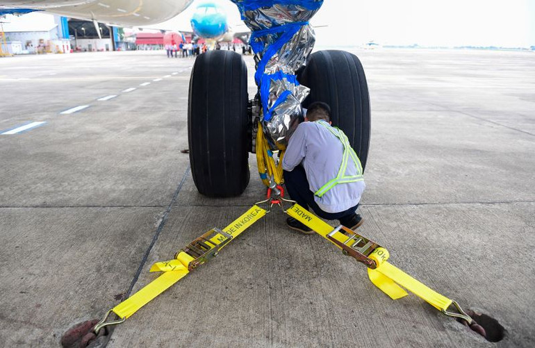 Các kỹ sư cẩn thận cố định dây, bọc kín các bộ phận quan trọng của máy bay trước khi bão số 3 đổ bộ vào miền bắc.