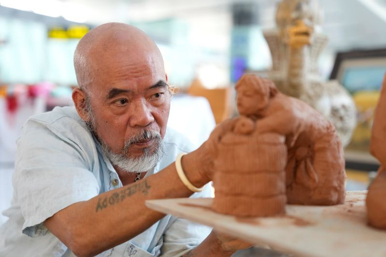 Nhà điêu khắc Đỗ Bá Quang với tác phẩm được thực hiện tại Nhà ga T2 Nội Bài.