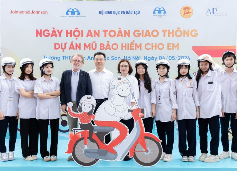 Ông Greig Craft, Chủ tịch Quỹ AIP, ông Lê Kim Thành, Phó Chủ tịch chuyên trách Ủy ban An toàn giao thông Quốc gia và đại diện Johnson&Johnson Việt Nam tặng mũ bảo hiểm cho các em học sinh.