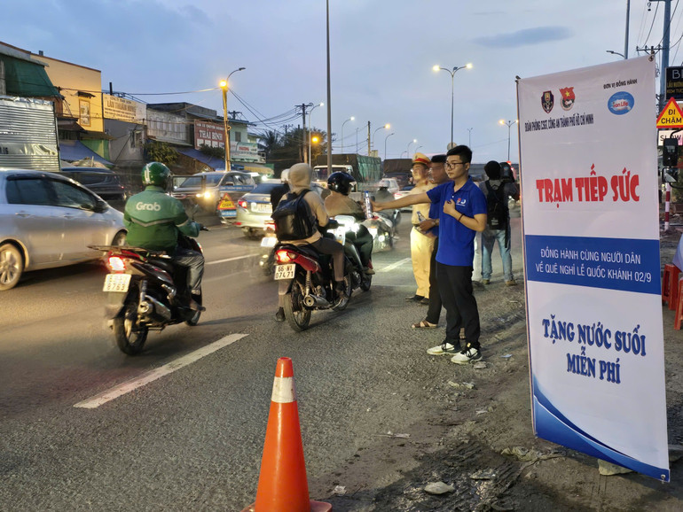 Các đoàn viên thanh niên cùng cảnh sát giao thông tham gia phát nước suối cho người dân lưu thông về quê nghỉ Lễ.