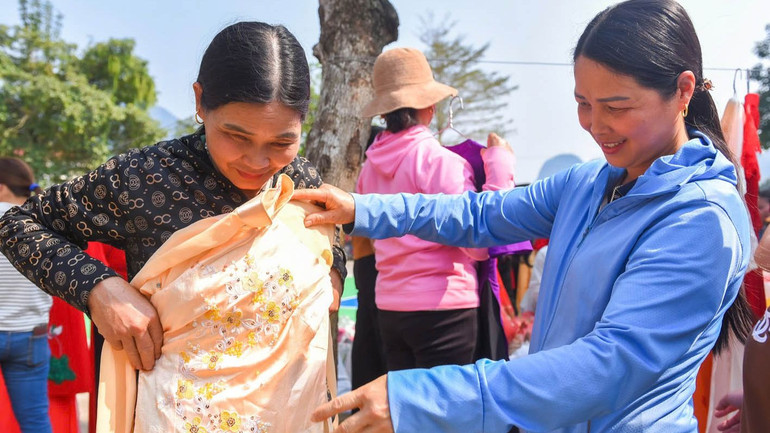 Chị em phụ nữ xã Linh Hồ vui mừng nhận những tà áo dài truyền thống. (Ảnh: Khánh Linh)