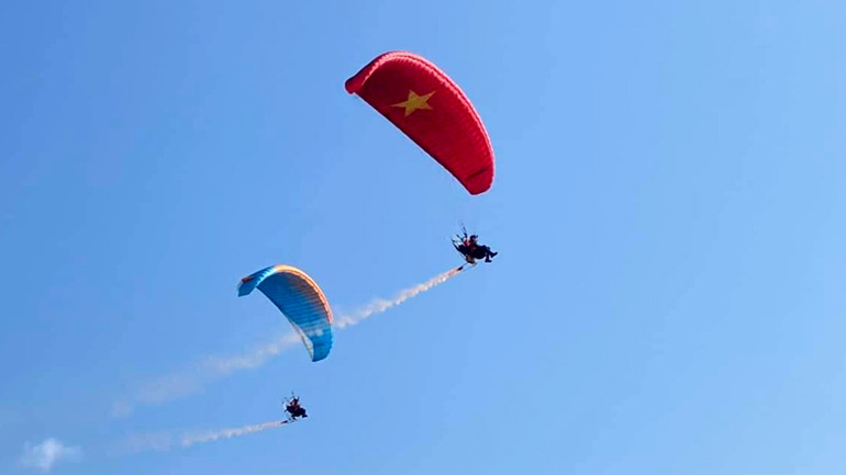 Các vận động viên bay trình diễn dù máy trước khi khai mạc giải.