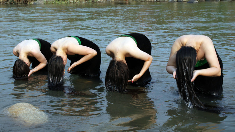 Tái hiện tục gội đầu của phụ nữ Thái bên suối.