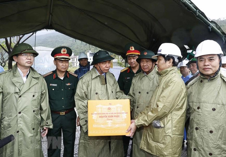 Chủ tịch nước Nguyễn Xuân Phúc tặng quà cho các lực lượng đang triển khai công tác khắc phục thiệt hại các công trình hạ tầng tại điểm sạt cuối đường Lê Văn Lương, Hoàng Sa, phường Thọ Quang, quận Sơn Trà. (Ảnh: Thống Nhất/TTXVN)