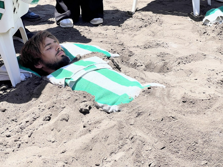 Vasily Bulshuf, một du khách 46 tuổi đến từ Ba Lan, bị bệnh vẩy nến, đang vùi mình trong cát đen trên bãi biển Safaga ở Safaga, Ai Cập, ngày 5/5. (Ảnh: Tân Hoa Xã)