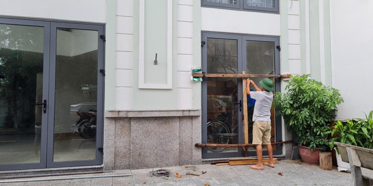 Ông Lê Hữu Xuân đang gia cố cửa cho ngôi nhà, sau khi đã giúp người dân trong tổ chằng buộc nhà cửa.